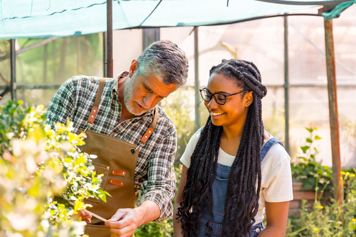 Nursery owner showing a younger colleague how to check a plant