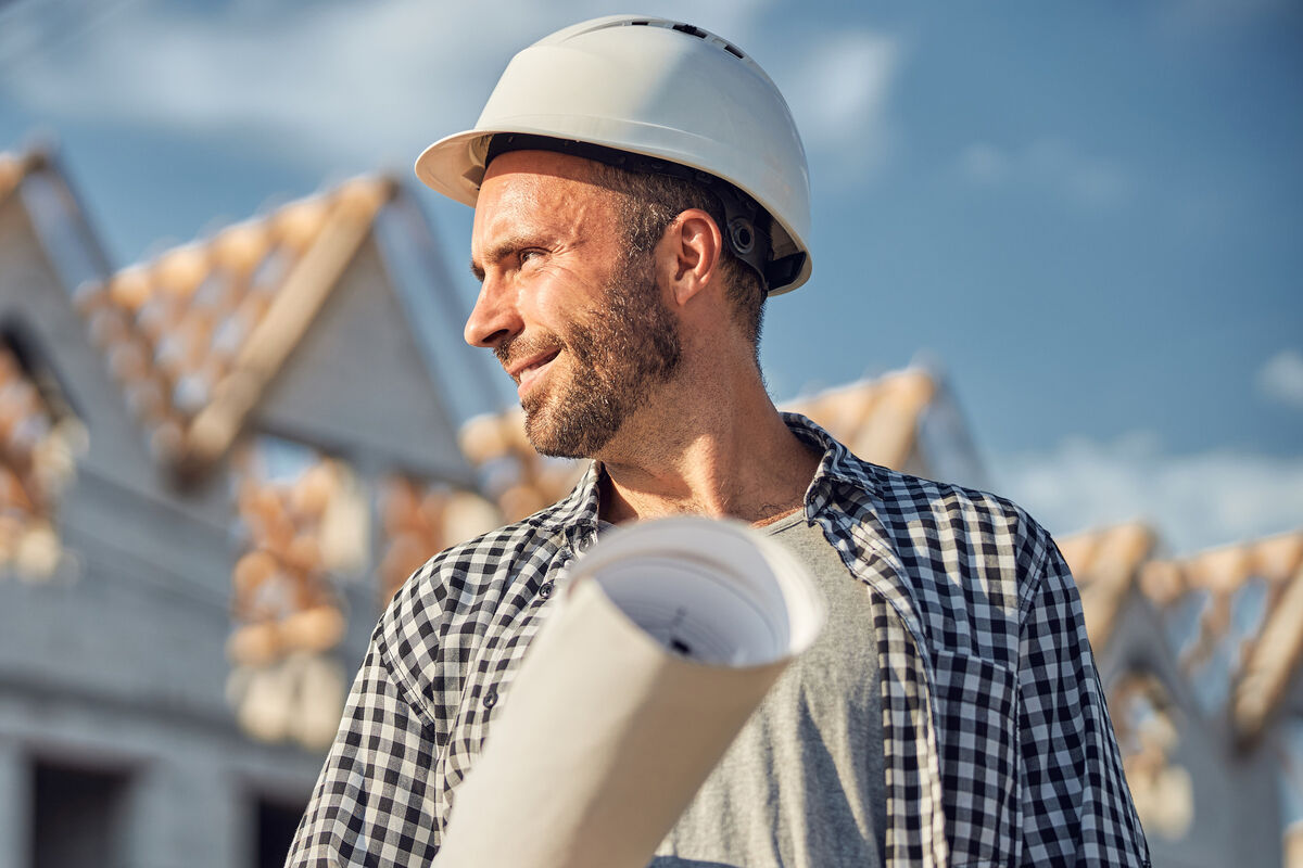 Contractor holding rolled plans on a framing site